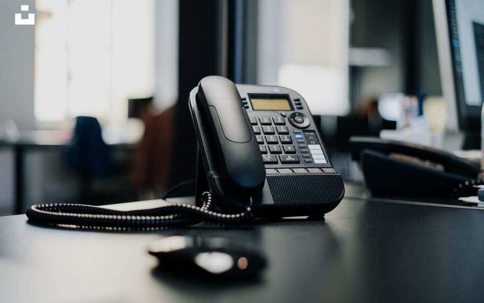 Teléfono IP de sobremesa comercial con auricular y teclado numérico en mesa de oficina