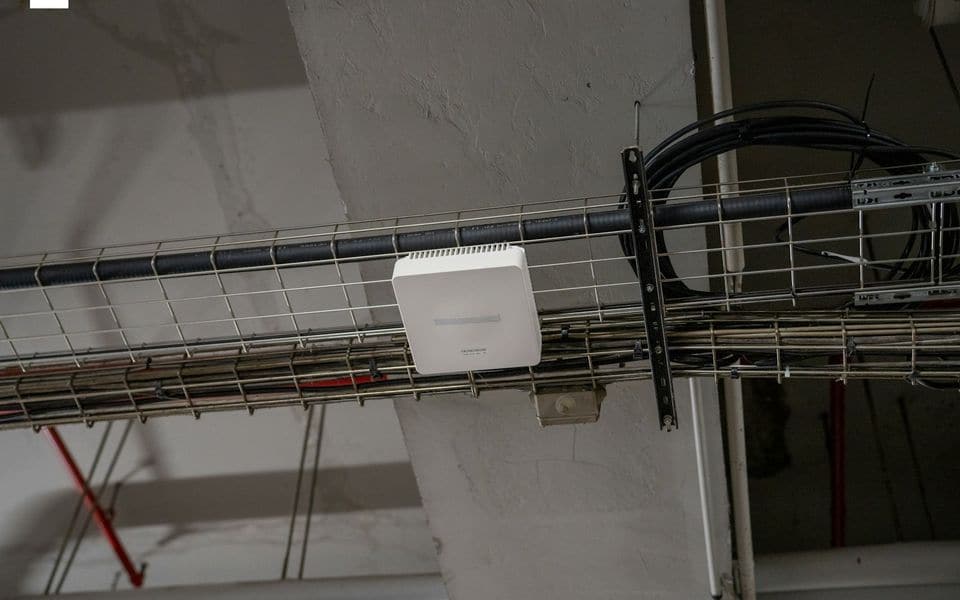 Enterprise wireless Wi-Fi access point mounted neatly on a technical cable tray