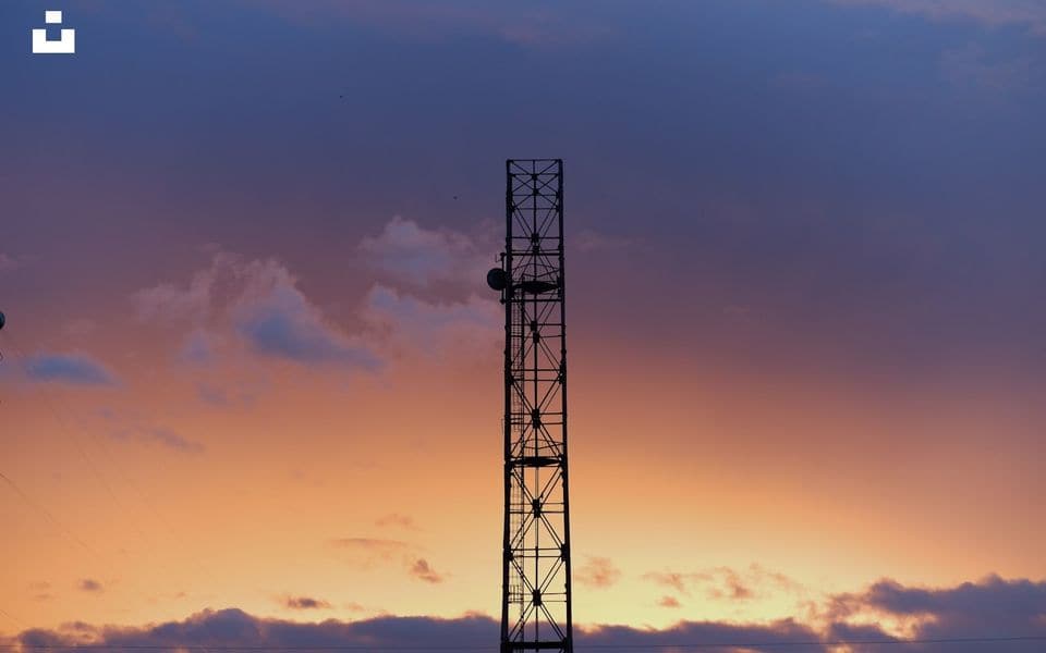 Telecommunications and wireless antenna mast lattice tower against sunset sky